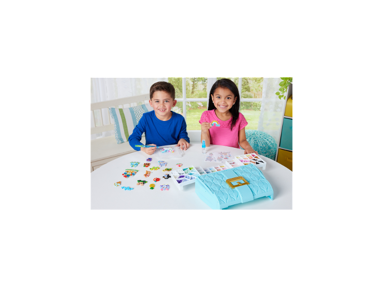 Twee kinderen maken kleurrijke kralenfiguren aan tafel met een knutselset.