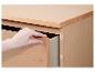 Hand opent lade van licht houten ladekast.