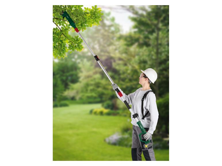 Vrouw snoeit takken in een tuin met een uitschuifbare takkenschaar.