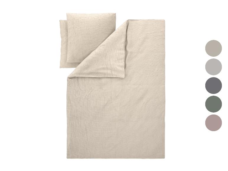Lichtbeige beddengoedset met twee kussens en een dekbed, met een kleurenpalet ernaast.