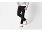 Man in zwarte corduroy broek, grijze hoodie en witte sneakers.