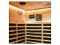 Interieur van een houten sauna met bedieningspaneel, luidspreker en lattenbanken.