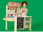 Kind speelt met een houten speelgoedwinkel met fruit, groenten en boodschappen.