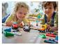 Twee kinderen spelen met LEGO Duplo raceauto's op de vloer.