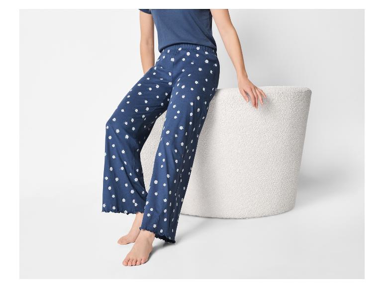Vrouw in donkerblauwe pyjamabroek met madeliefjesprint en bijpassend T-shirt, zittend.