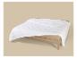 Wit gewatteerd dekbed op een licht houten bedframe met een beige hoeslaken.