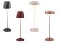 Vier moderne vloerlampen in zwart, rood, beige en koper, met geometrische en ronde kappen.