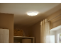 Ronde plafondlamp boven een plank met gevlochten manden en een gordijn.