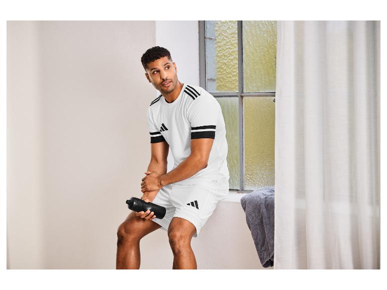 Man in wit Adidas T-shirt en korte broek met een zwarte waterfles.