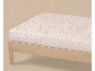 Hoeslaken met klein roze bloemenpatroon op een licht houten bedframe.