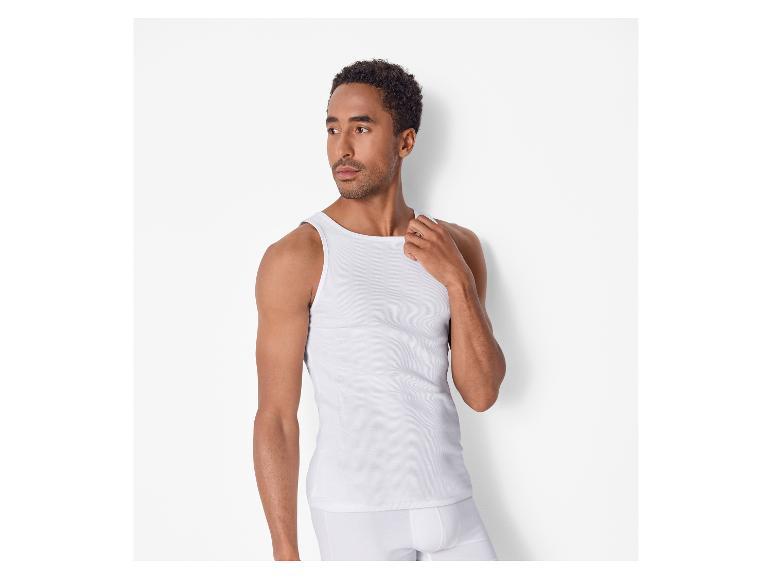 Man in een wit hemd en boxershort, opzij kijkend.