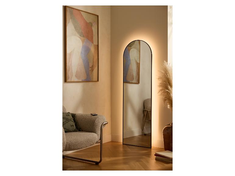 Verlichte spiegel in woonkamer met fauteuil en abstract schilderij.
