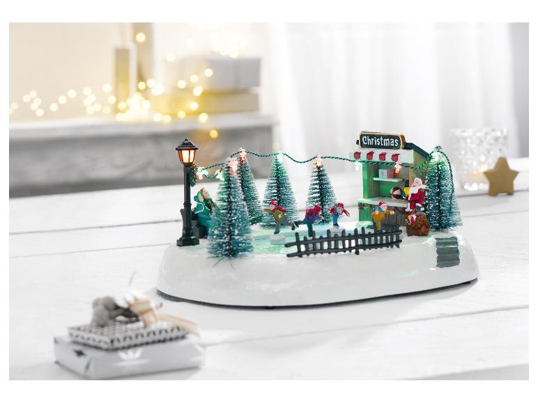 Kersttafereel met schaatsbaan, de Kerstman en feestelijke lichtjes op een witte tafel.
