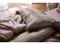 Gestreept beddengoed en een zachte deken in een slaapkamer.
