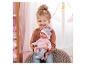 Lachend meisje houdt babypop vast in roze kleding en muts.