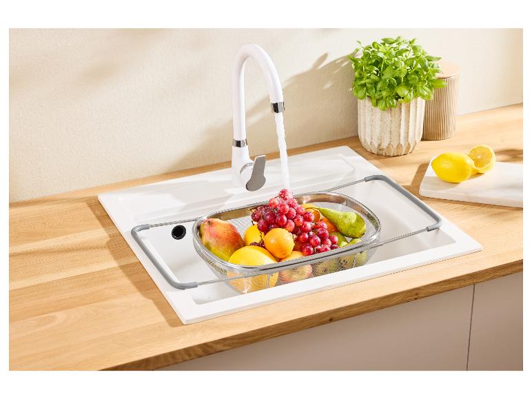 Witte keukenkraan met fruit in een vergiet in de gootsteen en citroenen op het aanrecht.