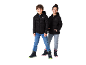 Twee kinderen in zwarte gewatteerde jassen, jeans en winterlaarzen, lachend naar de camera.