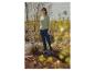 Vrouw in groene trui en donkerblauwe jeans, staand in een natuurlijke omgeving.