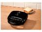 Zwart tosti-apparaat met twee sneetjes brood op een bord op een houten ondergrond.