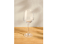 Leeg wijnglas op een houten tafel met schaduwen op de achtergrond.