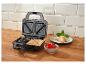 Open tosti-apparaat met tosti's, cherrytomaten en basilicum op een houten tafel.
