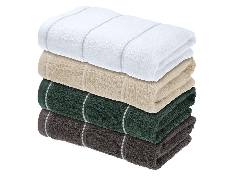 Een stapel van vier gevouwen handdoeken in wit, beige, groen en bruin.
