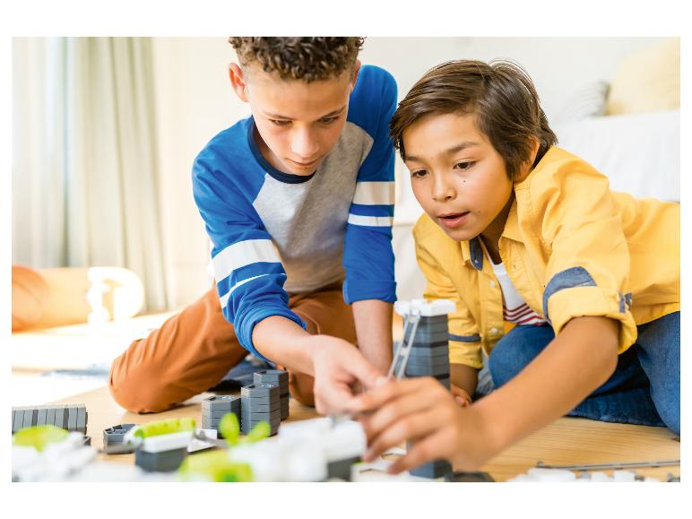 Twee jongens bouwen een constructie met bouwblokken op de vloer.