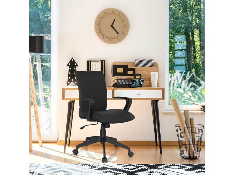 Een zwarte bureaustoel met armleuningen, een bureau en een vintage typemachine in een modern kantoor.