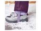Grijze kinderschoenen met paarse broekspijpen in de sneeuw.