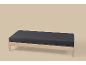 Een houten bedframe met een donkergrijs matras op een lichtbeige achtergrond.