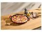 Pizza met salami, rode ui en paprika in een gietijzeren pan op een houten tafel.