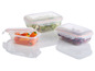Drie plastic lunchboxen met salade, kersen en paprika's.