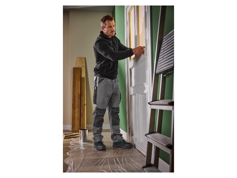 Man in werkkleding bereidt een deur voor om te schilderen.