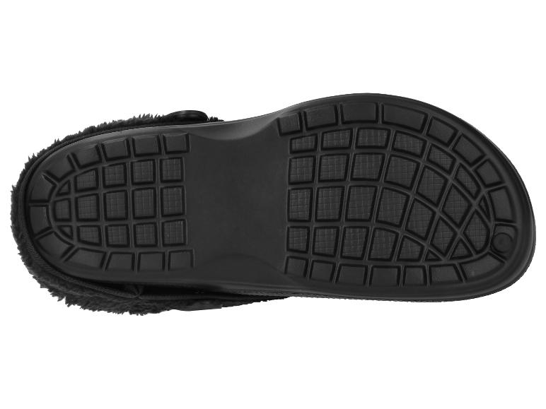 Onderkant van een zwarte pantoffel met een gestructureerde zool en pluizige voering.