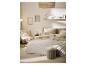 Slaapkamer in neutrale tinten met bed, fauteuil, wandplank en vloerkleed.