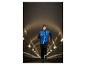 Man rent in een tunnel, draagt een blauw-zwart jack en een muts met licht.