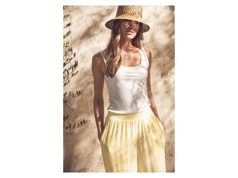 Vrouw in ESMARA® tanktop en gele broek met strohoed.