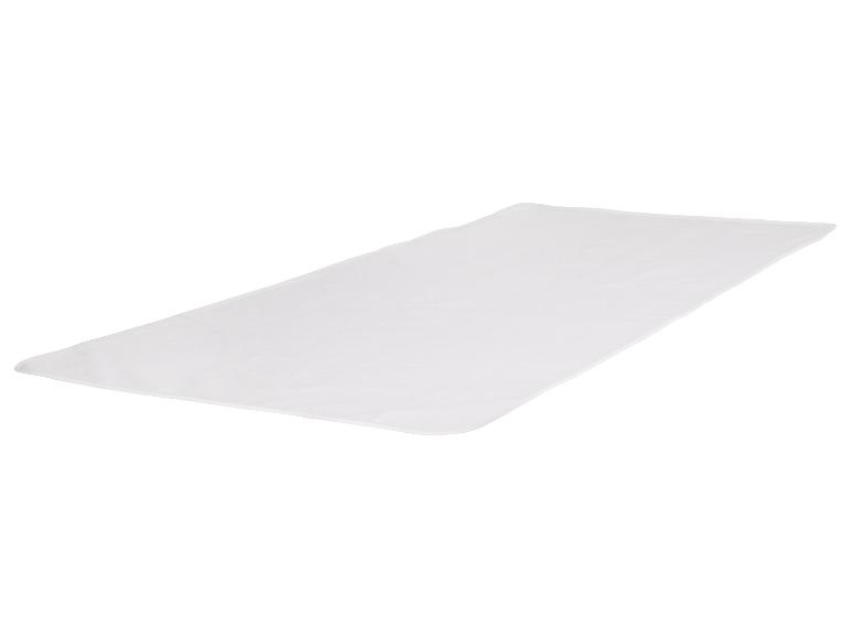 Een witte, rechthoekige deken uitgespreid op een wit oppervlak.