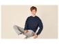 Jongen in een donkerblauwe sweater en grijze joggingbroek, zittend op een witte kruk.