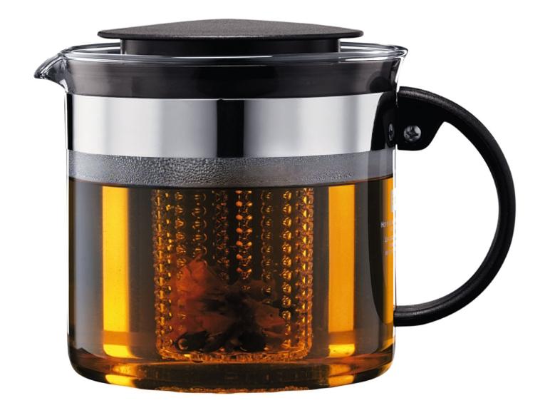 Glazen theepot met zwart deksel en handvat, gevuld met amberkleurige thee en een theezeef.