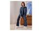 Vrouw in ESMARA® wide leg jeans en spijkerjasje zittend op een dressoir.
