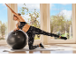 Vrouw in sportkleding traint op een mat met een fitnessbal.