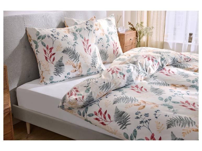 Bed met wit beddengoed met bladpatroon en grijs hoofdeinde.