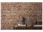 Een moderne houten kast met decoratieve items, waaronder een sculptuur, vaas en kaarsen, tegen een bakstenen muur.