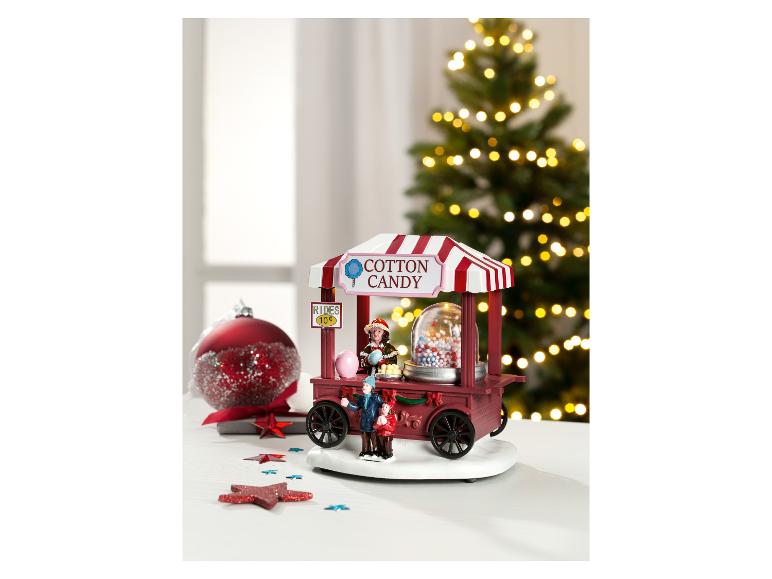 Kerstdecoratie suikerspinwagen met beeldjes en een rode kerstbal.