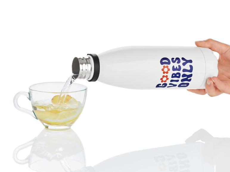 Een witte waterfles met de tekst 'Good Vibes Only' wordt in een glas met citroensap gegoten.