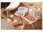 Vrouw gebruikt elektrische manicure- en pedicureset, met schoonheidsproducten in de buurt.