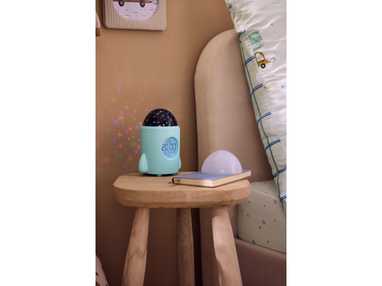 Kinderwekker in de vorm van een raket met sterrenprojector op een nachtkastje