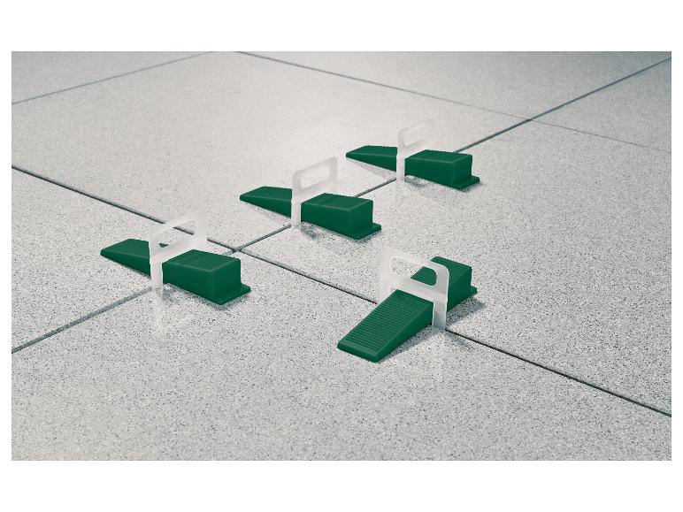 Tegelnivelleersysteem met groene wiggen en witte clips op grijze tegels