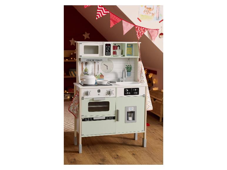 Een houten speelkeuken met een magnetron, fornuis, gootsteen en koelkast, versierd met slingers.
